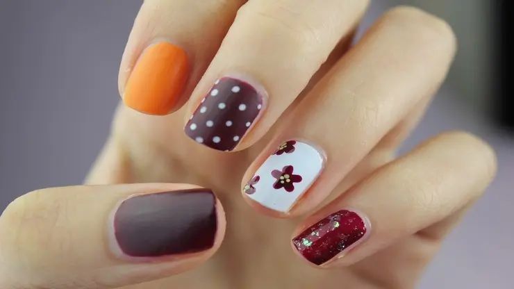 una mano di una donna in primo piano che ha tutte le unghie decorate con smalti differenti, l'immagine rappresenta il corso di manicure e pedicure curativa
